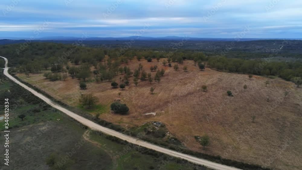 Aerial, pan, drone shot of a dirt road, in middle of forest and wilderness in cabeza de framontanos, cloudy day, Castile and Leon, Spain Aerial, pan, drone shot of a dirt road, in middle of forest and wilderness in cabeza de framontanos, cloudy day, Castile and Leon, Spain
