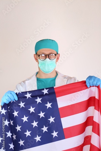 Viral diseases in the United States. coronavirus in America. Doctor in a medical protective mask with American flag in his hand. Medicine and health in the USA.Covid -19
