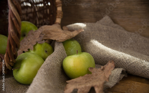 Fresh green apples with basket , dry leaves and burlap background