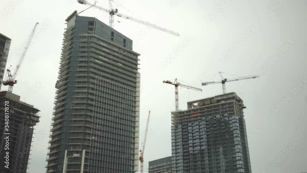High-rise Buildings Under Construction With Tower Cranes Erected Against The Dramatic Sky - Tilt Down Shot High-rise Buildings Under Construction With Tower Cranes Erected Against The Dramatic Sky - Tilt Down Shot