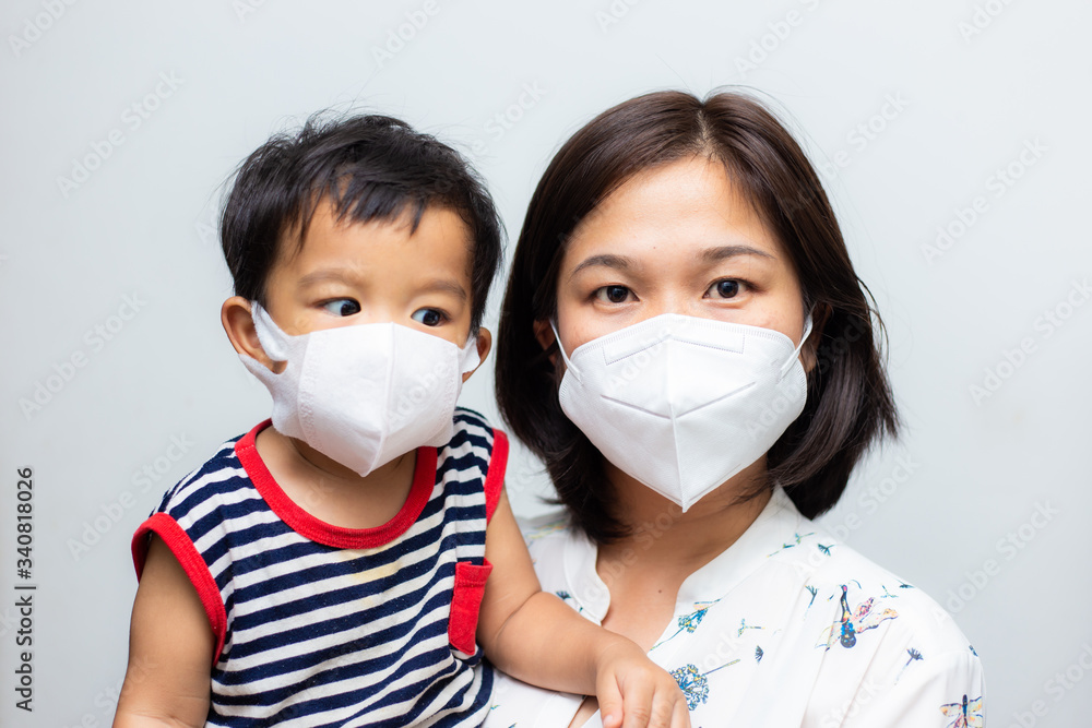 Asian mother holding her son wearing protective mask against covid 19 virus and PM 2.5 air pollution