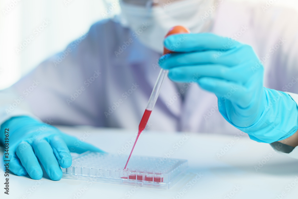 Pipette adding fluid to test tubes. laboratory assistant analysing a blood sample. Pipette adding fluid to test tubes. laboratory assistant analysing a blood sample.