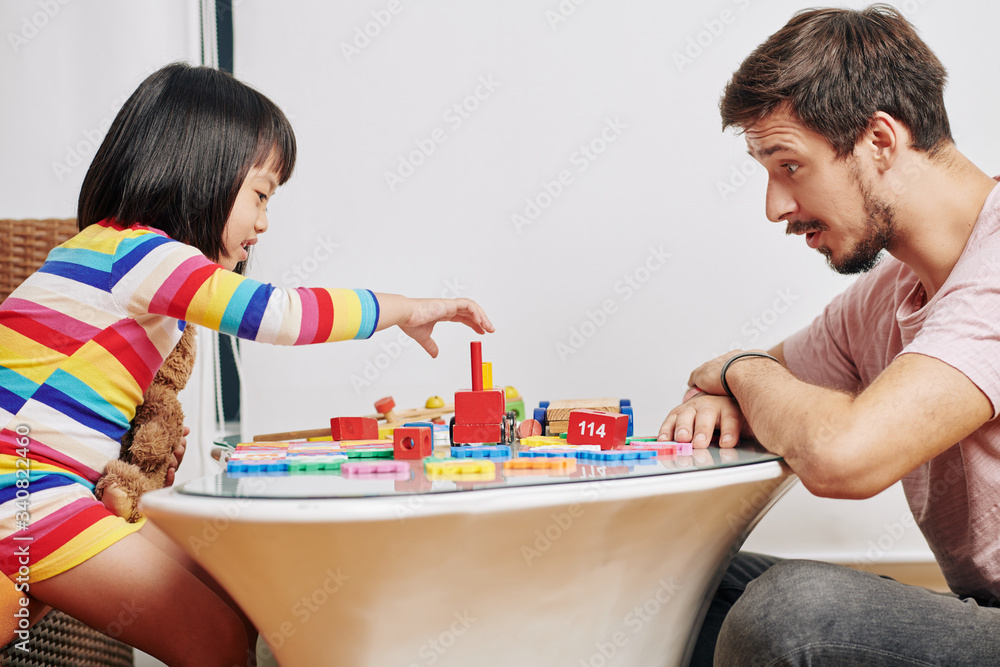 Young father and daughter enjoying playing with colorful wooden blocks Young father and daughter enjoying playing with colorful wooden blocks
