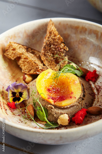 Rabbit liver pate with peach  honey and nuts in beige bowl