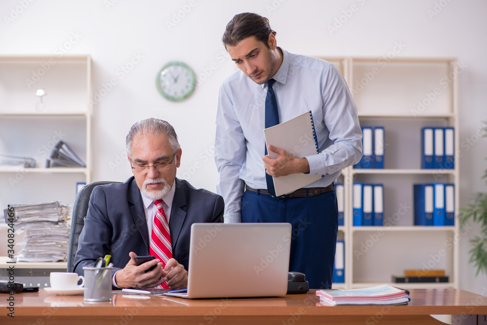 Old boss and young male employee in the office Old boss and young male employee in the office
