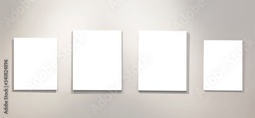 Four empty isolated on white paintings on the wall with gallery lighting. Space for text.