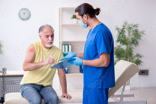Injured old man visiting young male doctor traumatologist © Elnur