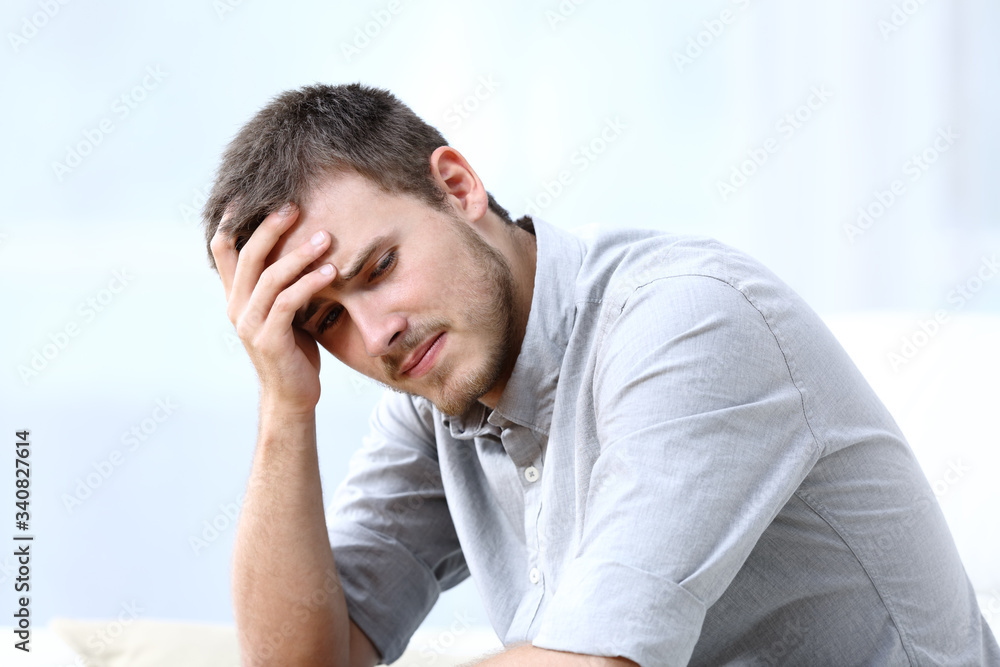 Sad worried man complaining on a couch at home Sad worried man complaining on a couch at home
