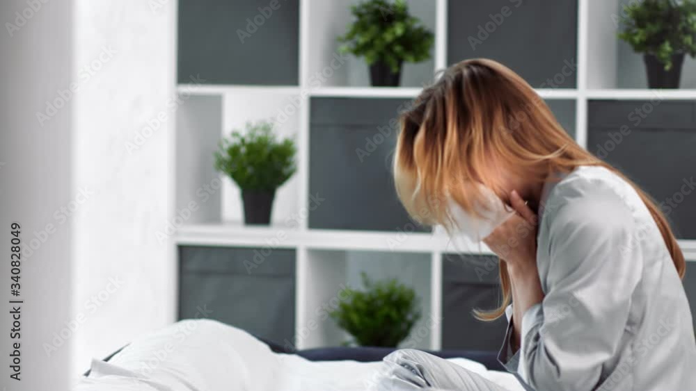 Sick young domestic woman in pajamas sneezing in tissue having flu. Medium shot on RED camera Sick young domestic woman in pajamas sneezing in tissue having flu. Medium shot on RED camera