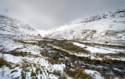 Snow and ice covered mountain ridges in the Lake District on a cold winters day. In the distance is Lower Man, Catstye Cam on the left with Glenridding Beck in the foreground.