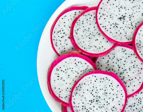 Closeup of a plate of dragon fruit slices on blue background