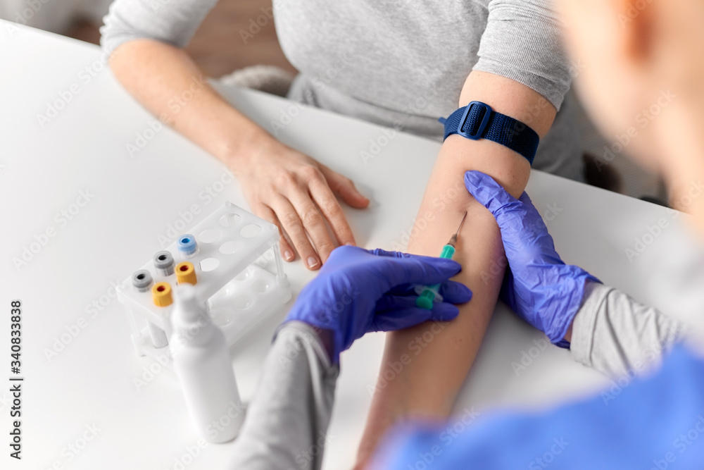 Fototapeta premium medicine, healthcare and diabetes concept - close up of doctor in gloves with syringe taking blood for test from patient's hand at hospital