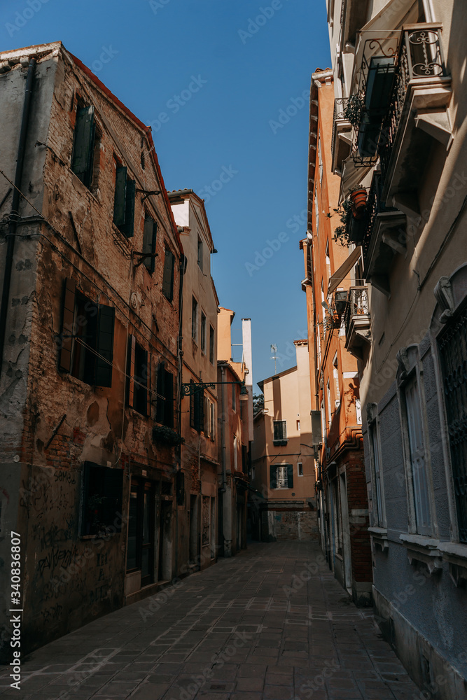 A narrow street in Venice between ancient stone houses on a Sunny day | VENICE, ITALY - 16 SEPTEMBER 2018. 
