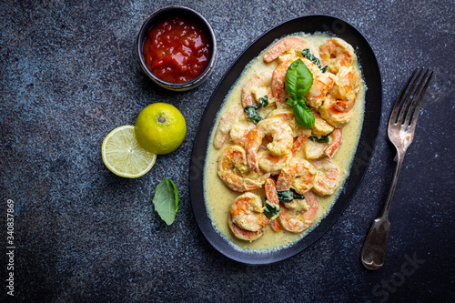 Shrimps in cream sauce with Coconut milk on a plate over black background, top view or view from above, flat lay