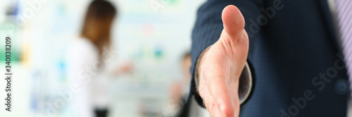 Focus on man stretching out to shake hands with colleague or boss. Younger managers working on new business strategy for corporate people. Company meeting concept. Blurred background