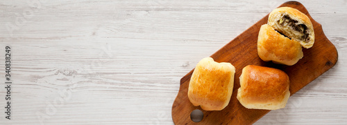 Home-baked Beef Russian Bierocks on a rustic wooden board on a white wooden surface, top view. Flat lay, overhead, from above. Space for text. photo