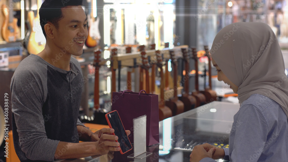 An upwardly mobile Asian Muslim man using a mobile phone - smartwatch to pay for a product at a sale terminal with nfc identification payment for verification and authentication An upwardly mobile Asian Muslim man using a mobile phone - smartwatch to pay for a product at a sale terminal with nfc identification payment for verification and authentication
