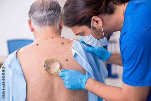 Old man visiting young male doctor dermatologist