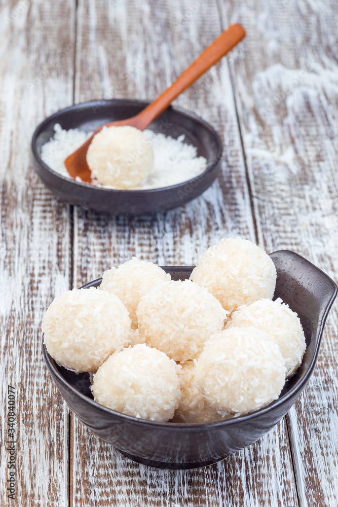 Healthy homemade raw paleo energy coconut balls in ceramic bowl, vertical Healthy homemade raw paleo energy coconut balls in ceramic bowl, vertical
