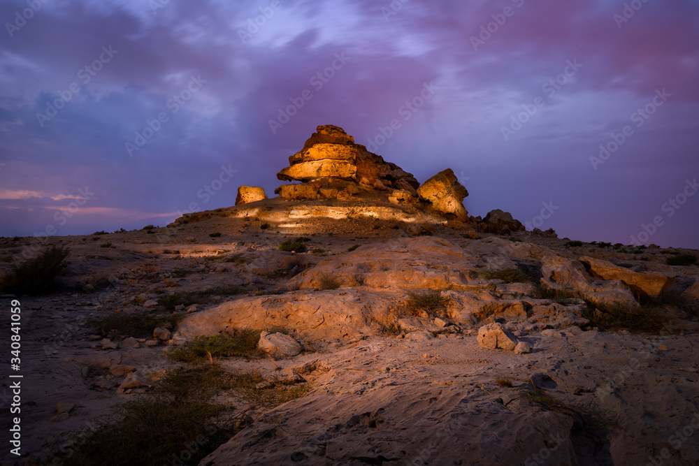 Beautiful view of rock hill also called Dragon Rock illuminated with striking clouds after sunset at Sakhir mountains, Bahrain.