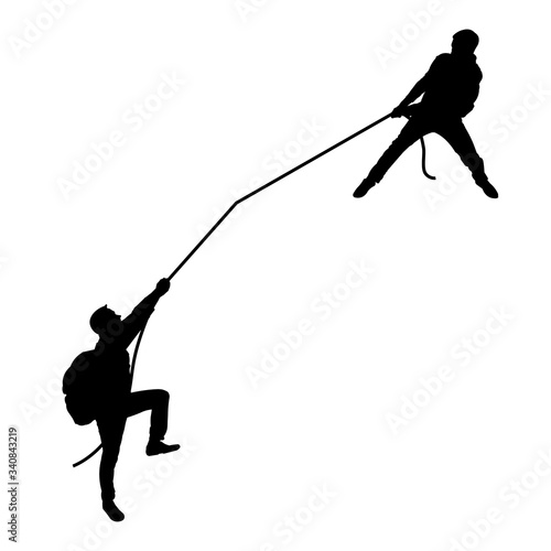 Black silhouette of men. The man pulls another rope. Teamwork. Tourists, travelers, climbers, adventurers, hiking. Mountain trip.