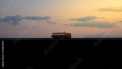 Sewage truck passing by at sunset.Cars for cleaning the sewer system of the city. Special equipment, utility service. Underexposed pic. © majorstockphoto