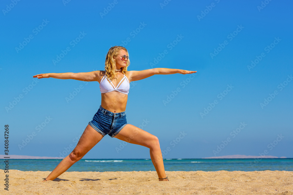 Blonde woman practices yoga poses on beach Blonde woman practices yoga poses on beach