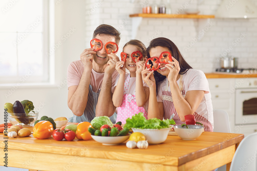 Happy family smiling at a table with fresh vegetables make salad in the kitchen. Happy family smiling at a table with fresh vegetables make salad in the kitchen.