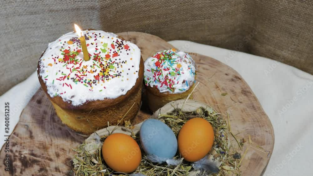 Easter cake with a burning candle. Easter eggs in the nest. Easter decoration. Attributes of the Christian holiday of the resurrection Easter cake with a burning candle. Easter eggs in the nest. Easter decoration. Attributes of the Christian holiday of the resurrection