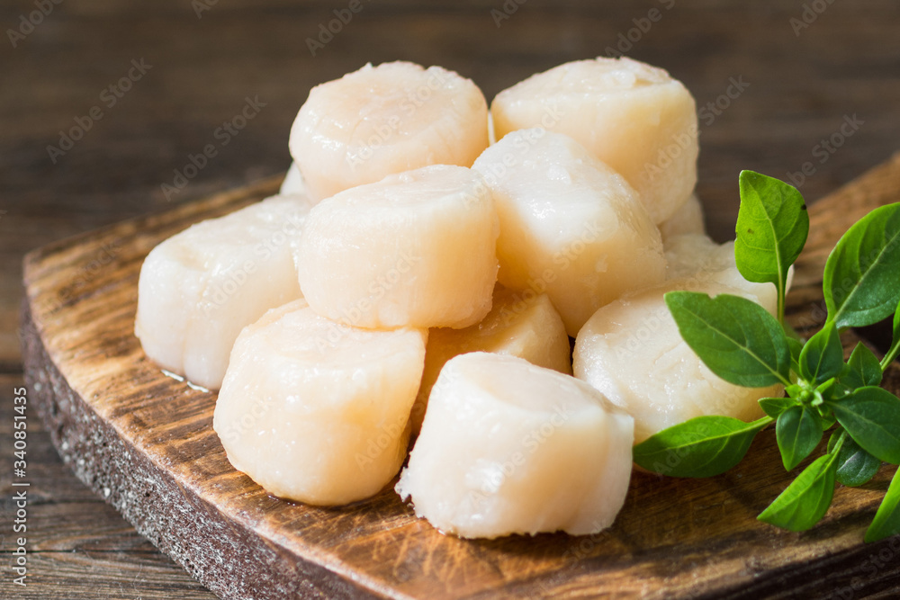 Scallops on a wooden Board on a brown wooden table. Scallops close up