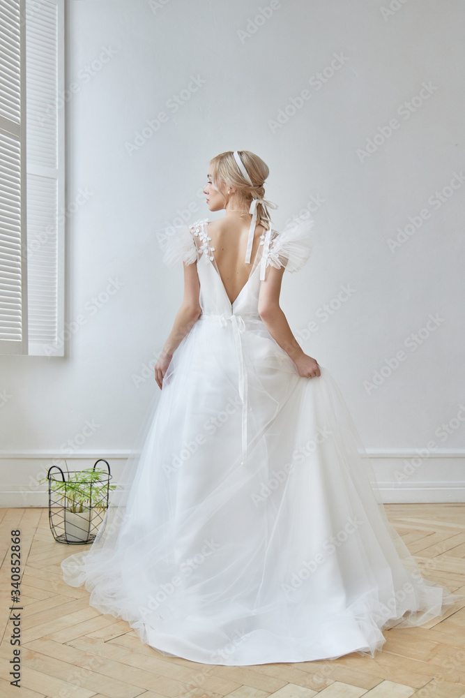 Luxurious white wedding dress on the girl's body. New collection of wedding dresses. Morning bride, a woman waiting for the groom before the wedding ceremony. Young bride in a long dress