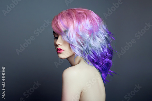 Portrait of a woman with bright colored flying hair, all shades of purple. Hair coloring, beautiful lips and makeup. Hair fluttering in the wind. Sexy girl with short hair. Professional coloring