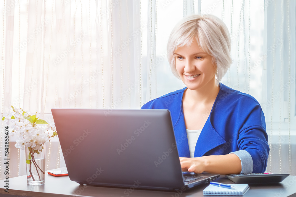 Happy smiling business woman working on a laptop remotely from a home office. Freelance, quarantine, distance learning, remote work concept. Happy smiling business woman working on a laptop remotely from a home office. Freelance, quarantine, distance learning, remote work concept.