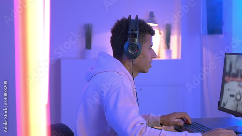 фотографія Medium shot of young black gammer in headphones playing in online shooter