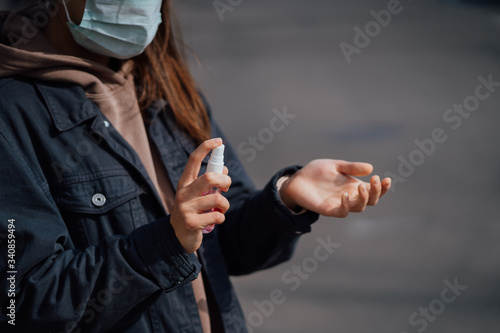 Caucasian girl disinfects her hands with sanitizing spray.