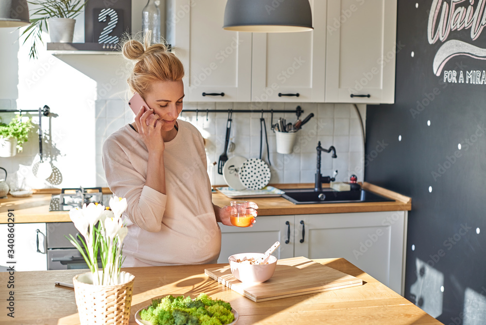Happy cute blonde phoning and making dinner in bright kitchen Happy cute blonde phoning and making dinner in bright kitchen