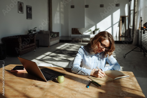 Designer woman makes some scetches. Working from home. Bright sun and long shadows