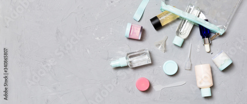 Top view of means for face care: bottles and jars of tonic, micellar cleansing water, cream, cotton pads on gray background. Bodycare concept with empty cpace for your ideas