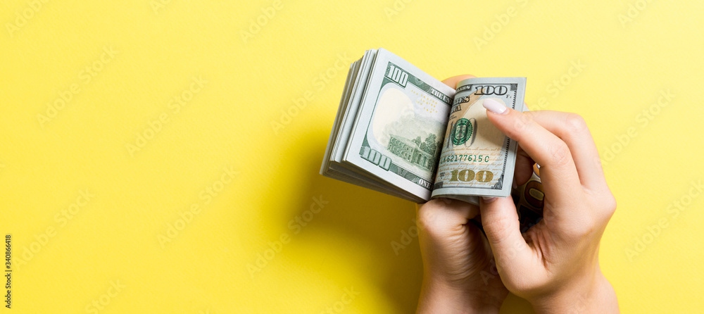 Businesswoman's hands counting one hundred dollar bills on colorful background. Salary and wage concept with copy space. Top view of Investment concept Businesswoman's hands counting one hundred dollar bills on colorful background. Salary and wage concept with copy space. Top view of Investment concept