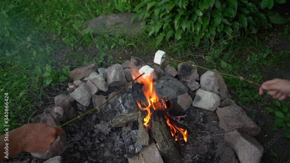 Father and son having fun during vacations in camping. People cooking white bbq marshmallow over burning camping fire flame. Father and son having fun during vacations in camping. People cooking white bbq marshmallow over burning camping fire flame.