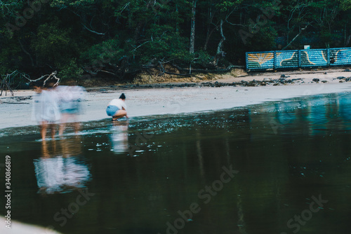 Women on the sand in slow shutter of women in the water at Burleigh National Park, Gold Coast, Australia