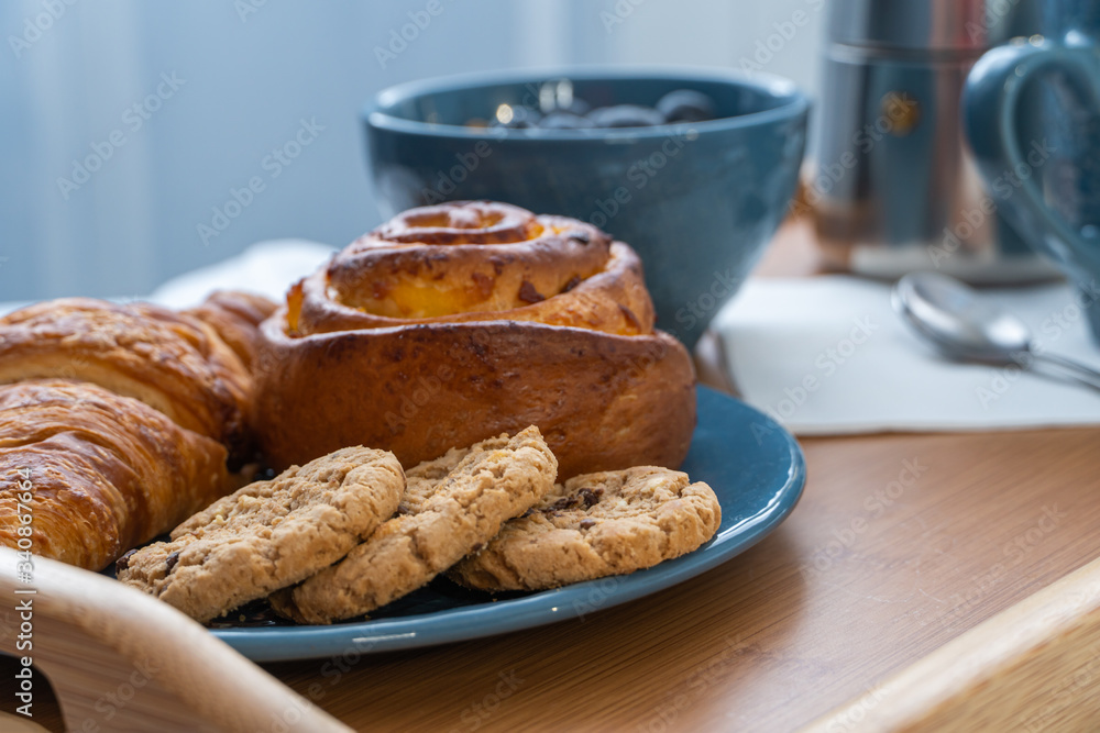 Breakfast served in bed on wooden tray with coffee and croissants Breakfast served in bed on wooden tray with coffee and croissants