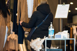 Blond girl in a shop with mask and plastic gloves, shopping during covid or coronavirus lockdown, disinfectant, gloves and tissues at the entrance
