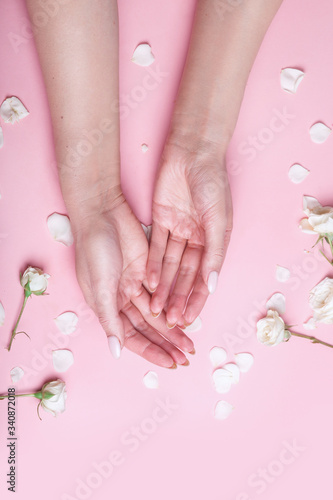 Elegant and graceful womans hands on pink background with flowers