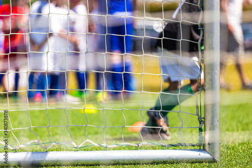 Football goal with a side net. Soccer background. Soccer goalkeeper and reserve substitute players on bench in the background