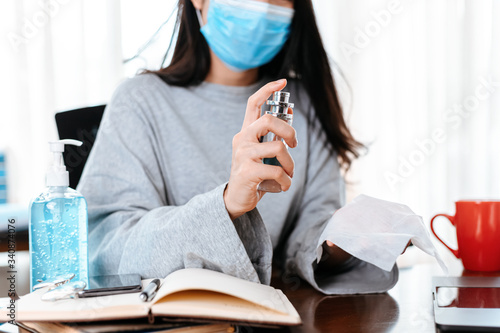 Woman cleaning her hands with a tissue.  Business woman working from home wearing protective mask.