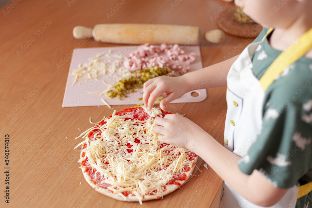 child cook preparing pizza in his kitchen