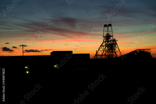 The setting sun behind silhouetted headgear at South Crofty tin mine which closed in 1998, the last to close in europe
