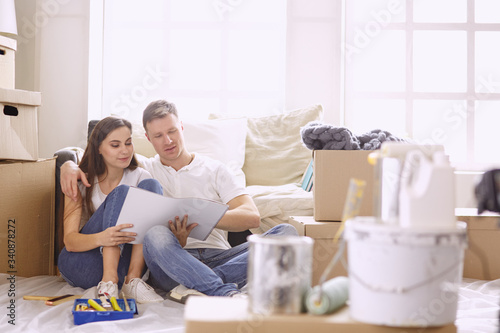 Young Hispanic couple looking at blueprints of new home, high angle view