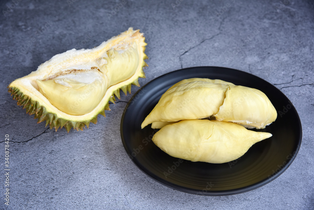 Durian riped. King of Fruits. Durian is a popular tropical fruit in Thailand. Betel of durian on black dish with durian peel on Dark color background. Seasonal fruit concept. Selected focus. Durian riped. King of Fruits. Durian is a popular tropical fruit in Thailand. Betel of durian on black dish with durian peel on Dark color background. Seasonal fruit concept. Selected focus.